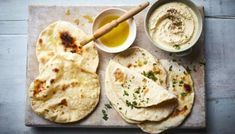 some pita bread and dip are on a cutting board