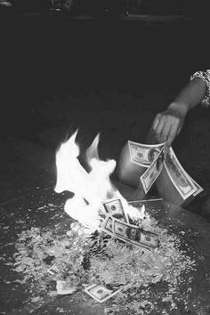 a person sitting in front of a fire with money