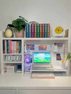 a white desk topped with a laptop computer next to a book shelf filled with books