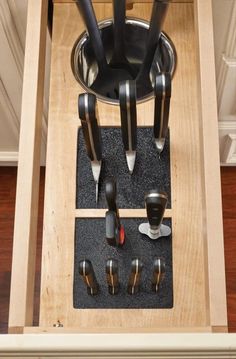 an open drawer with knives and other kitchen utensils in it on the floor