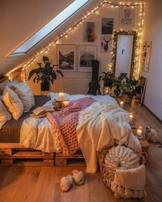 an attic bedroom is decorated with string lights and blankets on the bed, along with candles