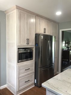 a kitchen with white cabinets and stainless steel refrigerator freezer next to an island in the middle