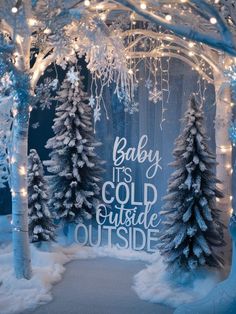 a winter scene with snow covered trees and baby it's cold outside sign in the middle