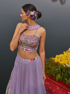 A three-piece lilac floral lehenga set from the Nikita Tiwari collection. This beautiful lilac floral pleated lehenga is paired with a printed bustier blouse. The lilac color with hand-embroidery work enhances the graceful georgette lehenga. The hand-embroidered blouse has intricate pearl-sequin details with floral print. The outfit is completed with a long floral jacket in viscos georgette material. Purple Sleeveless Wedding Set, Fitted Lavender Floor-length Set, Lavender Floral Embroidered Sets For Wedding, Fitted Purple Sharara With Floral Embroidery, Lavender Fitted Sets For Reception, Fitted Lavender Set For Reception, Fitted Purple Sets With Floral Embroidery, Fitted Lavender Sharara For Reception, Purple Wedding Sets For Spring