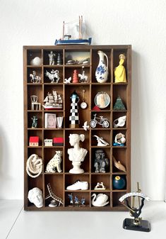 a book shelf filled with assorted figurines on top of a white table