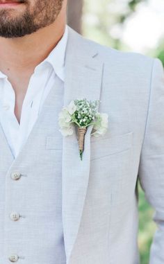 a man in a gray suit with a boutonniere and flowers on his lapel