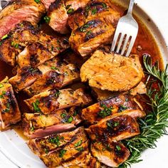 grilled pork chops with rosemary garnish on a white platter, ready to be served