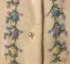 an embroidered sweater with flowers and pearls on it