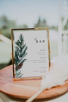 a bar sign sitting on top of a wooden table next to a white and gold feather