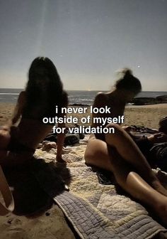 two women are sitting on the beach with their backs to each other