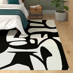 a white and black area rug in a bedroom next to a bed with green pillows