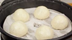 four doughnuts sitting in a black pan on top of a stove