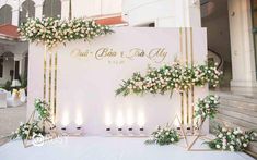 an outdoor event with flowers and greenery on the wall, decorated with gold geometric frames