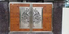 two wooden doors with metal tree designs on the front and side panels, in an outdoor area