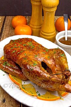 a large piece of meat sitting on top of a white plate next to oranges