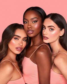 three beautiful women posing together in front of a pink background