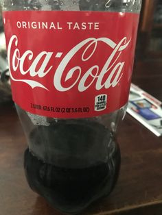 a bottle of coca cola sitting on top of a wooden table