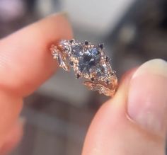 a close up of a person's hand holding a ring with a blue diamond in it