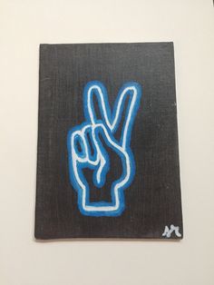 a blue peace sign painted on top of a black piece of paper