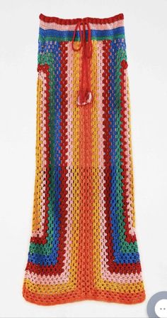 a colorful crocheted skirt is displayed on a white surface with an orange drawstring