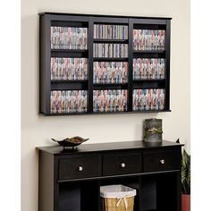 a black entertainment center with dvd's on the shelves and a basket in front of it