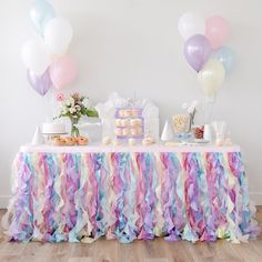 a table topped with cake and balloons on top of a hard wood floored floor