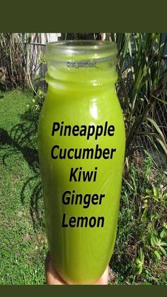 a hand holding a green glass jar that says pineapple cucumber kiwi ginger lemon