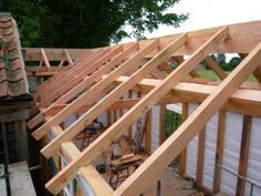 a house being built with wooden framing and roof trusses on the side of it