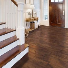 an entryway with wood floors and white railings next to a brown wooden door