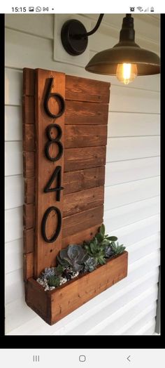 a wooden house number sign with succulents and plants in the planter