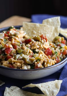 a bowl filled with salsa and tortilla chips on top of a blue napkin