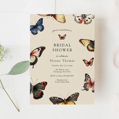 the butterfly bridal shower is shown on top of a table with flowers and greenery