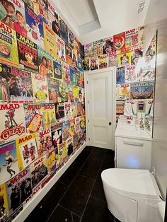 a bathroom with posters on the wall and a toilet in the corner next to it