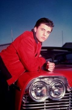 a man leaning on the hood of a red car