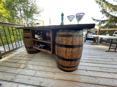 an outdoor bar made out of wine barrels on a deck with tables and chairs in the background