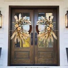 two wreaths on the front door of a house