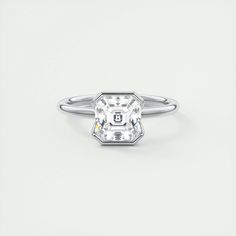 a white diamond ring with a center stone in the middle, on a plain surface