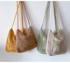 three crocheted purses hanging from hooks on a white wall, one is green and the other is yellow