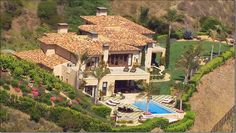 an aerial view of a house with a swimming pool and lush greenery on the hillside