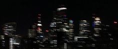 the city skyline is lit up at night with bright lights in the buildings and skyscrapers