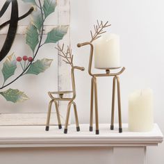 two candles sitting on top of a table next to a reindeer statue and candle holder