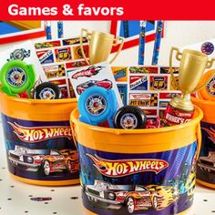 three buckets filled with hot wheels toys on top of a white table next to confetti sticks