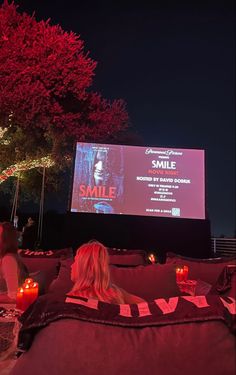 people sitting on bean bag chairs in front of a large screen with candles lit up