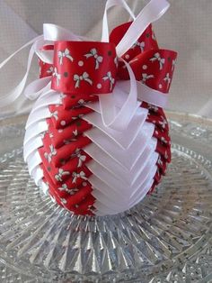 a red and white ornament sitting on top of a glass plate covered in ribbon