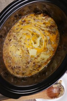 an overhead view of a crock pot filled with cheese and meat, sitting on a table