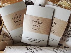 four cheese shop business cards sitting on top of each other in front of some hay