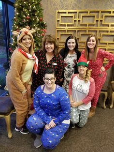 a group of women dressed up in pajamas posing for a photo with a christmas tree behind them