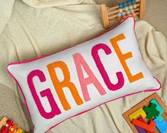 a pillow with the word grace on it next to wooden blocks and a toy truck