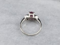 Always in style, rings such as this one can be worn as engagement rings, birthstone rings, or just for special occasions. We've set the center of this one with a high-quality, glowing red ruby. The side stones are bright white diamonds, reflecting plenty of light into the center stone. As an engagement ring will look well with a variety of bands, from a plain golden circle to a ruby and diamond eternity band. Metal: 14K White Gold Gem: Ruby 2.02 Carats Gem Measurements: 8.0 x 6.0 mm, Oval Accents: 8 Diamonds totaling .50 Carats, G in Color, SI1 in Clarity Ring Size: 6.75 Marks: “14K MFP” Stamped on the inside band Rings Birthstone, Gem Ruby, Ruby And Diamond Ring, Birthstone Rings, Pocket Watch Chain, Eternity Band Diamond, Red Ruby, Birthstone Ring, White Diamonds