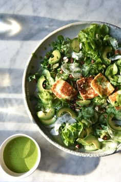 a bowl filled with salad next to a cup of green liquid